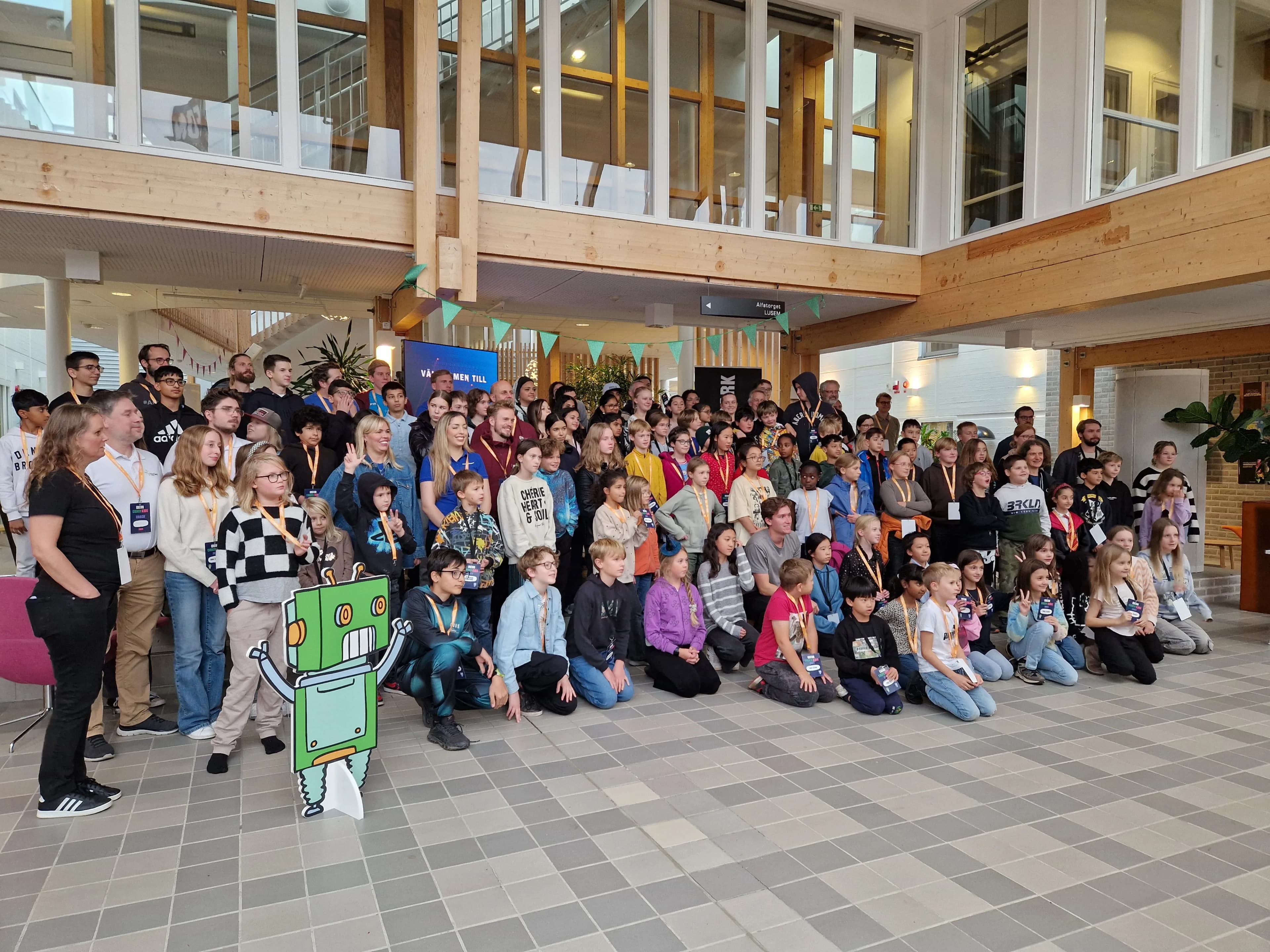 Gruppbild från Coder Kids 2024 med deltagare, coacher och en robotfigur