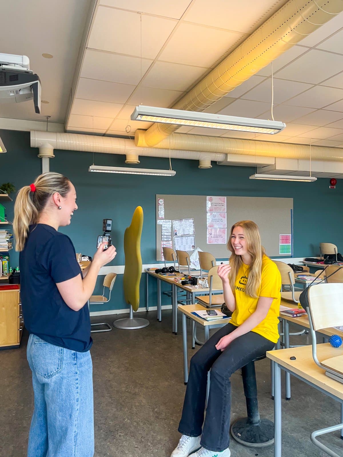 En praktikant filmar en ledare med mobilkamera i ett klassrum