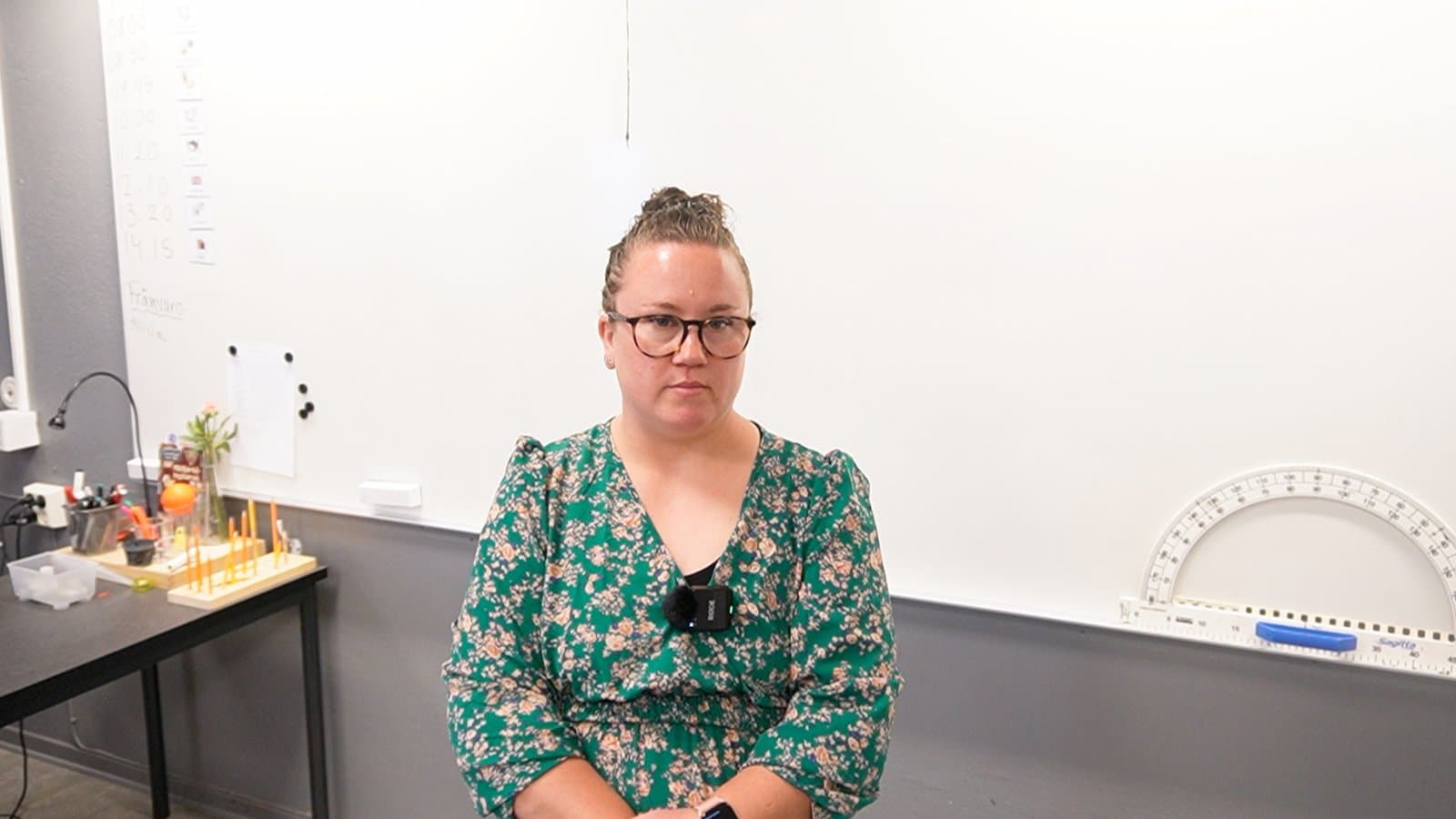 En lärare sitter framför whiteboarden i sitt klassrum