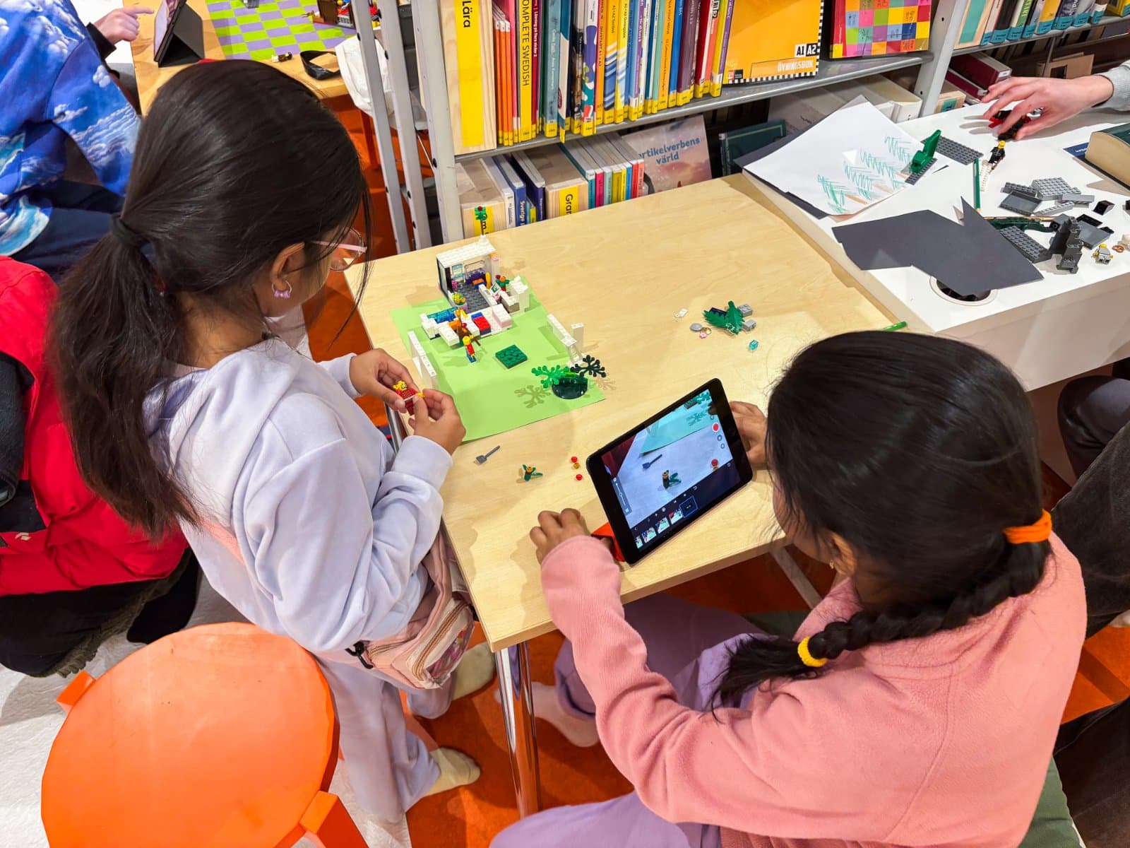 Två barn bygger en LEGO-scen och filmar den med en surfplatta